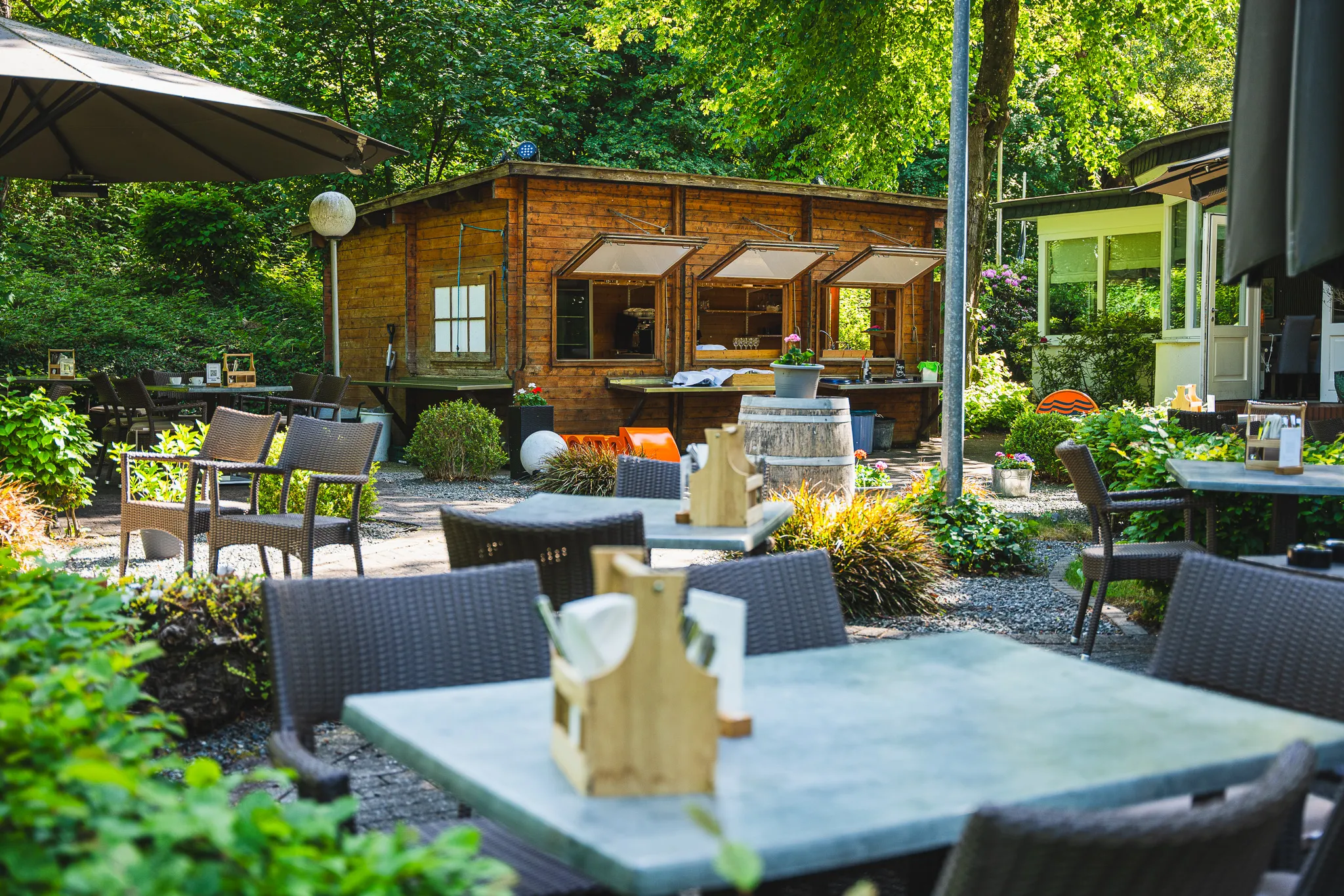 Eingedeckte Tische auf der Terrasse vor einem Holzgebäude.